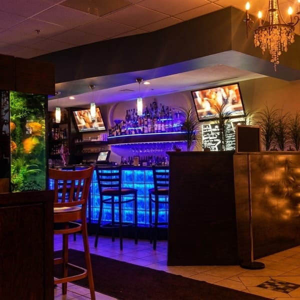 Restaurant interior with a large fish tank, a blue-lit bar, and a decorated Christmas tree.