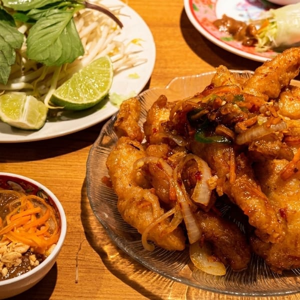 Crispy fried chicken with onions and peppers, served with fresh herbs, lime, and peanut sauce.
